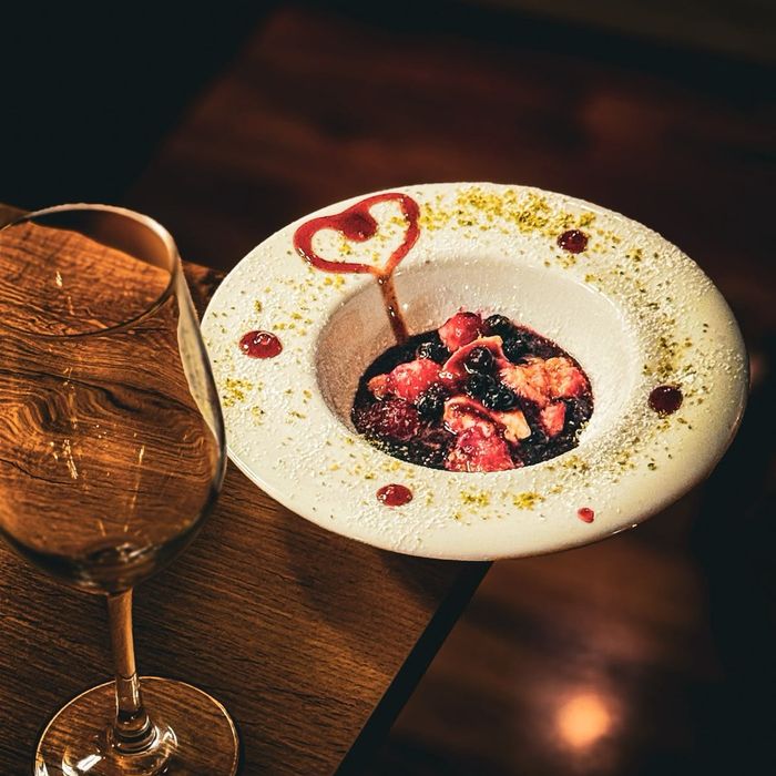 Dessert mit Waldbeeren und einem Herz aus Fruchtsoße