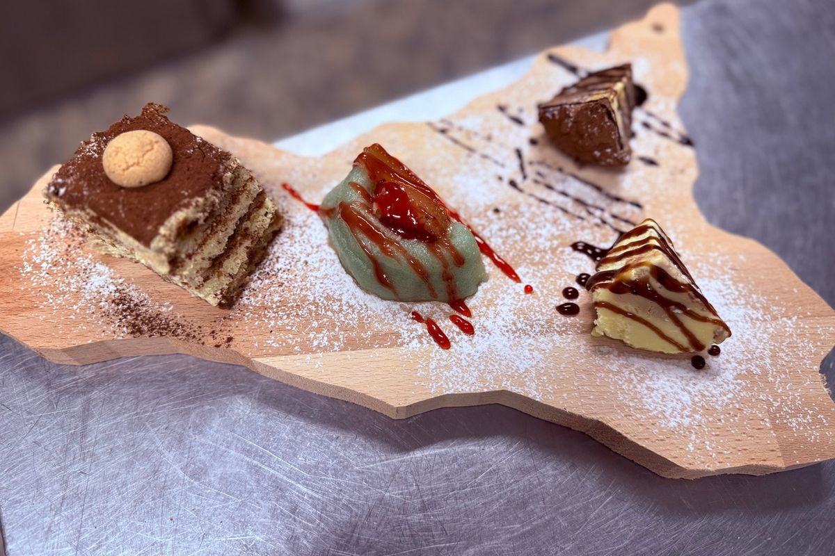 Tiramisu, Pistaziendessert und Schokoladentörtchen auf einem Holzbrett in Form von Sizilien