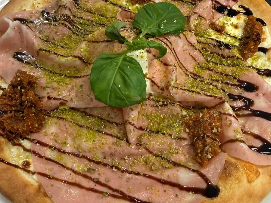 Pizza mit Mortadella, Pistazien, Basilikum und Balsamico